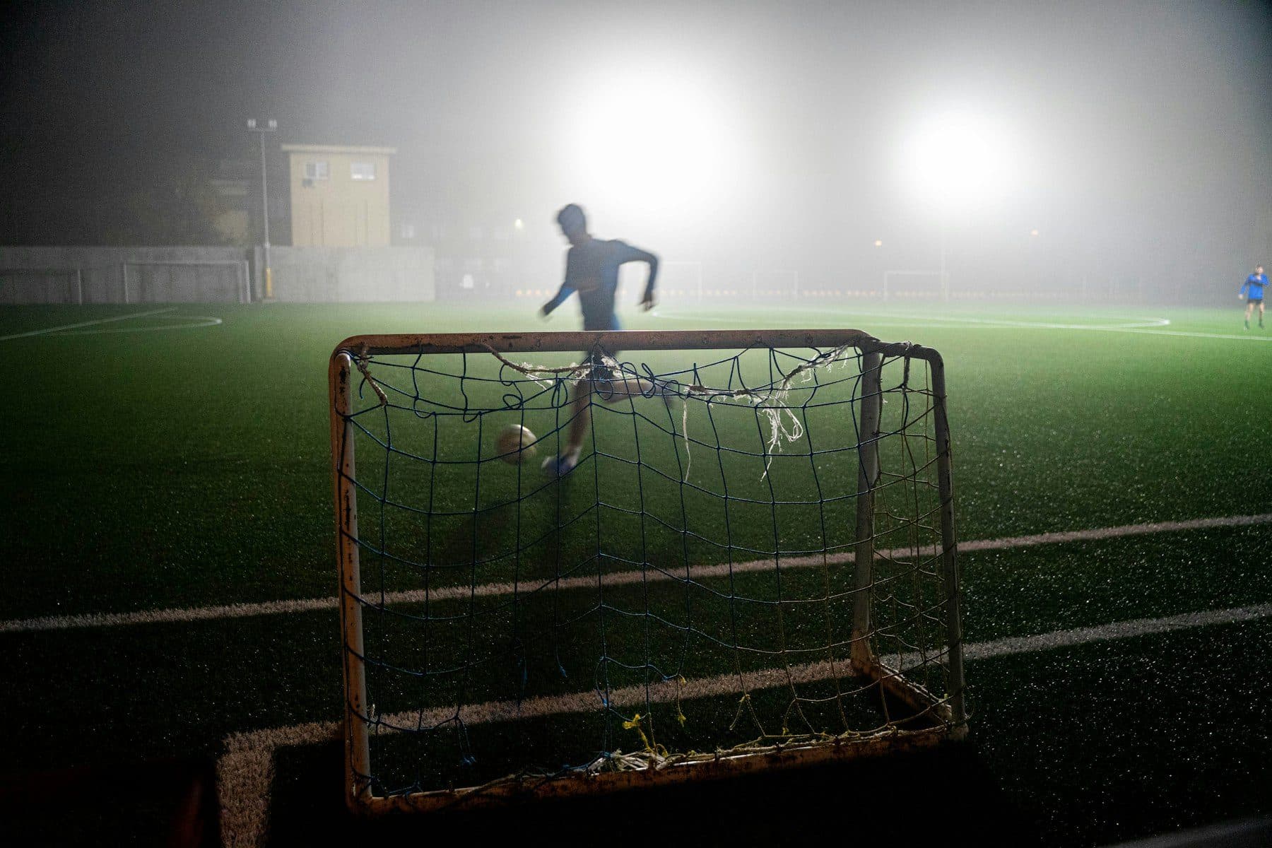 A single floodlight over a small goal, at night, in fog